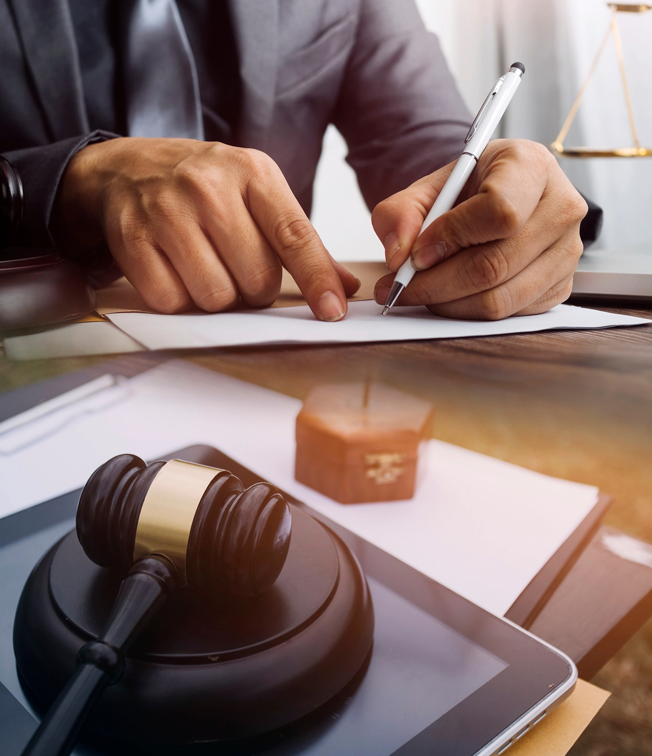 Lawyer writing with gavel and documents nearby.